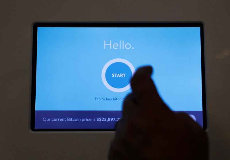 © Reuters. Ducatus franchise manager Philip Lim shows how he makes a deposit at a Bitcoin ATM during the opening of their cashless cafe that accepts cryptocurrencies such as Bitcoin in Singapore