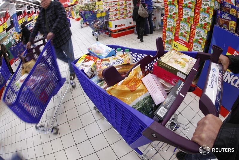 © Reuters. Customers push shopping trolleys down an aisle at Carrefour Planet supermarket in Nice Lingostiere