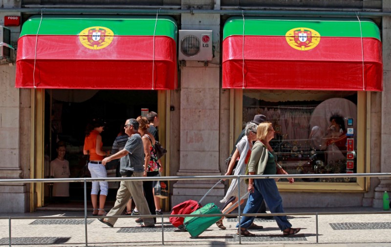 © Reuters. FILE PHOTO: People walk past a shop decorated with Portugal's national flags in downtown Lisbon