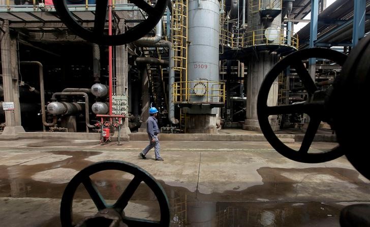 © Reuters. FILE PHOTO: A worker walks past oil pipes at a refinery in Wuhan