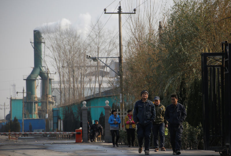 © Reuters. Smoke billows from a chimney as workers leave a factory in rural Gaoyi county near Shijiazhuang