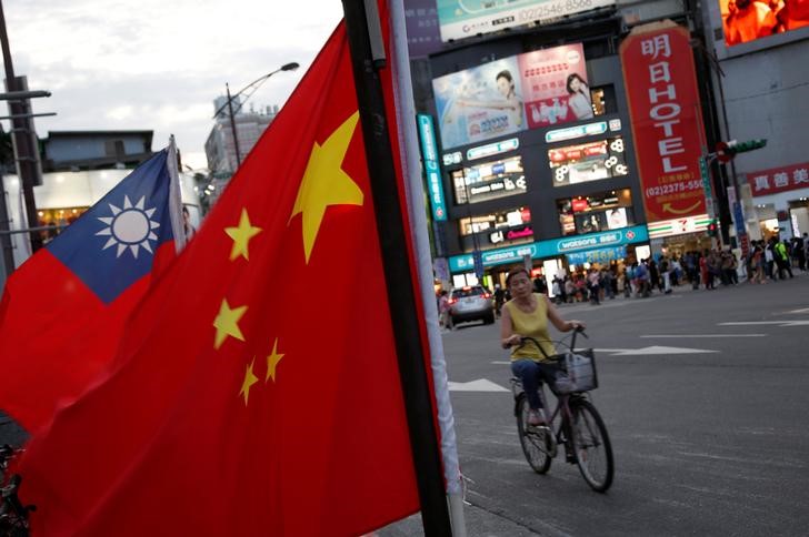 © Reuters. A woman rides a bike past Taiwan and China national flags during a rally held in Taipei, Taiwan May 14, 2016. REUTERS/Tyrone Siu