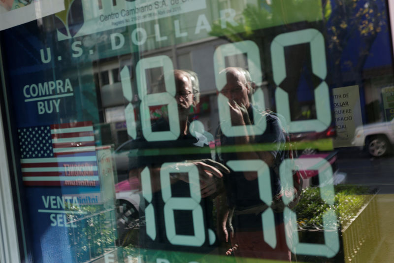 © Reuters. Tourists are reflected in a window as they look at a board displaying the exchange rate for Mexican peso and U.S. dollar at a foreign exchange bureau in Mexico City