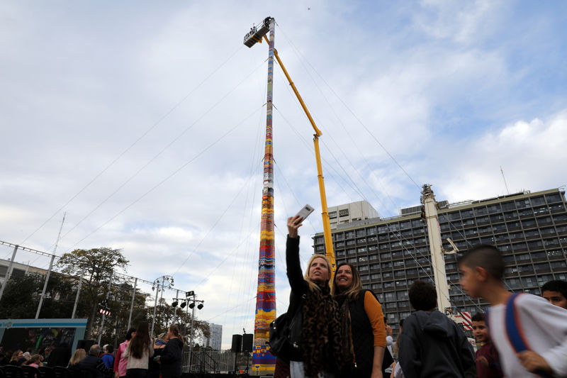 © Reuters. Mulher fotografa torre de tijolos de plástico de 36 metros em Tel Aviv