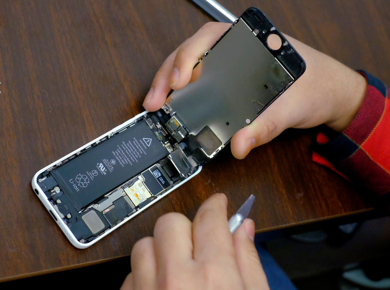 © Reuters. FILE PHOTO: A man tries to repair an iPhone in a repair store in New York