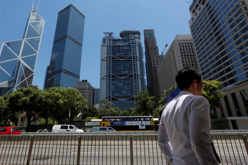 © Reuters. A man walks in front of the Bank of China Tower, Cheung Kong Center, HSBC bank and Standard Chartered bank at the financial central district in Hong Kong