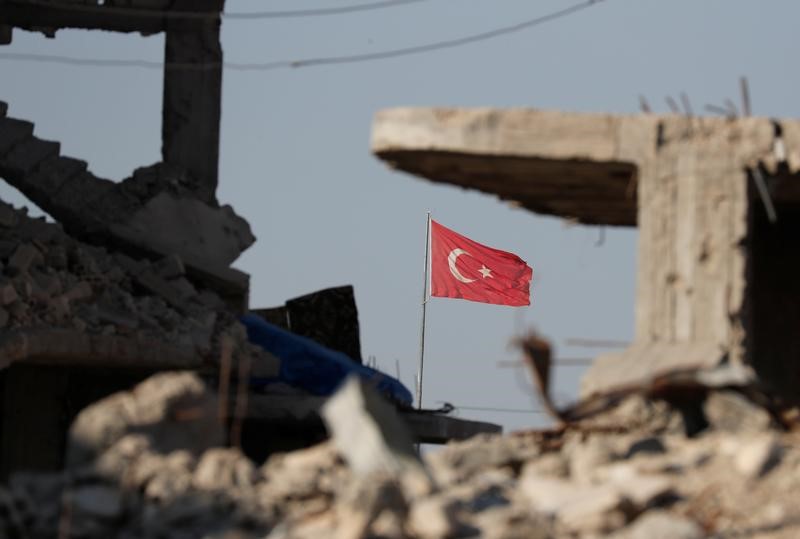 © Reuters. Turkish flag flutters at Turkey's border gate, as pictured on Syria side, overlooking the ruins of buildings destroyed during fightings with the Islamic State militants in Kobani