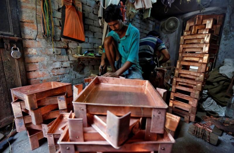 © Reuters. FILE PHOTO: A worker makes copper trays inside a workshop in Kolkata
