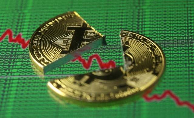 © Reuters. FILE PHOTO - Broken representation of the Bitcoin virtual currency, placed on a monitor that displays stock graph and binary codes, are seen in this illustration picture