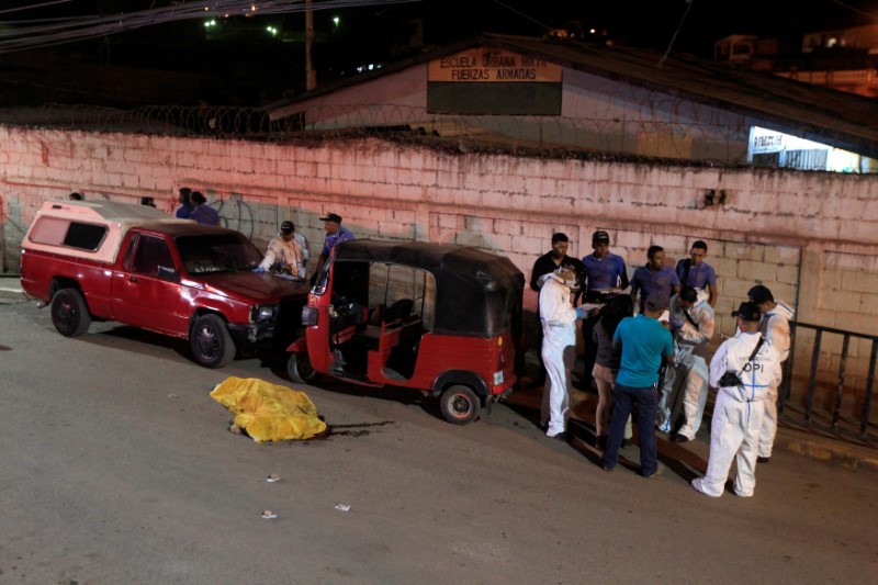 © Reuters. FILE PHOTO: Members of a forensic team work at a crime scene where gunmen killed five people at a working class neighbourhood in Tegucigalpa