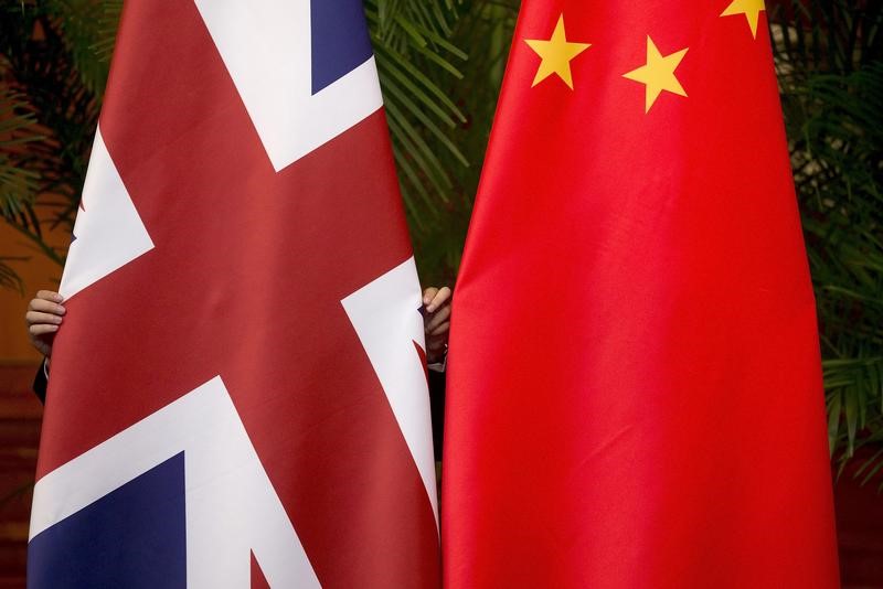 © Reuters. FILE PHOTO: A worker adjusts British and China national flags on display for a signing ceremony at the seventh UK-China Economic and Financial Dialogue "Roundtable on Public-Private Partnerships" in Beijing