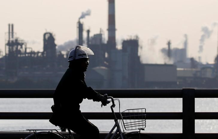 © Reuters. A worker cycles near a factory at the Keihin industrial zone in Kawasaki, Japan