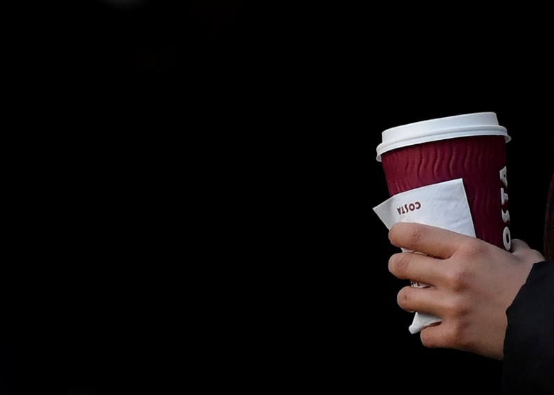 © Reuters. A commuter carries a disposable coffee cup in London, Britain