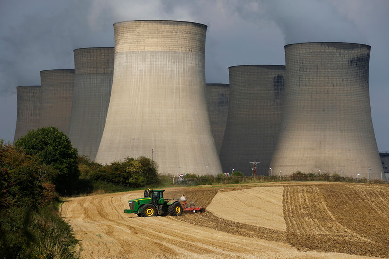 © Reuters. FILE PHOTO:A farmer works a field in the shadows of Ratcliffe-on-Soar Power Station