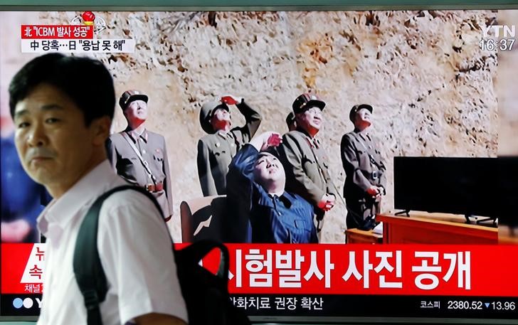 © Reuters. FILE PHOTO: A man walks past a TV broadcasting still photographs released by North Korea's state-run television KRT of North Korea's Hwasong-14 missile at a railway station in Seoul