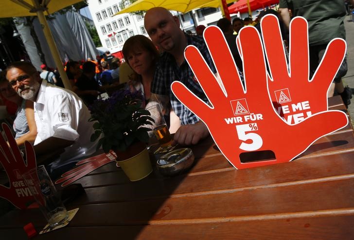 © Reuters. Signs with text 'We are for 5%' are pictured at a table in a cafe as steel workers of Germany's IG Metall union protest for higher wages in Cologne
