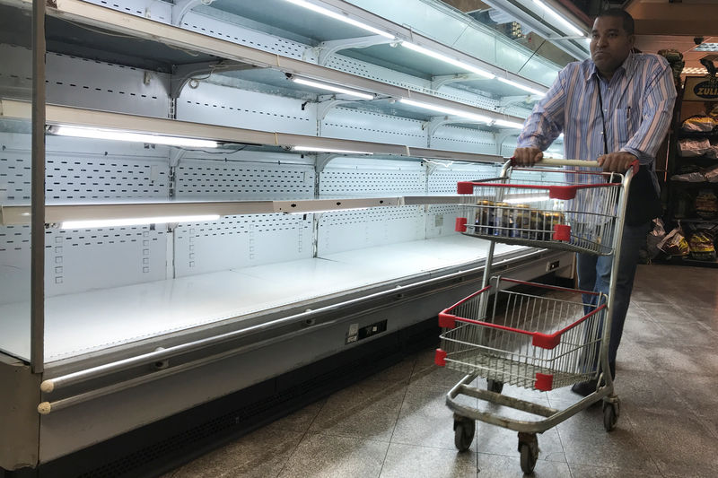 © Reuters. A man walks past an empty refrigerator at a supermarket in Caracas