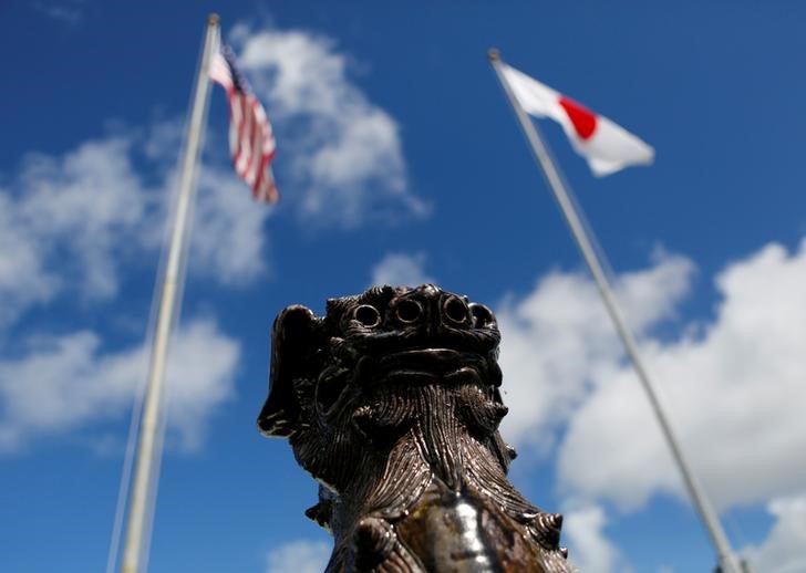 © Reuters. The U.S. and Japanese national flags are hoisted next to a traditional Okinawan Shisa statue at the U.S. Marine's Camp Foster in Ginowan