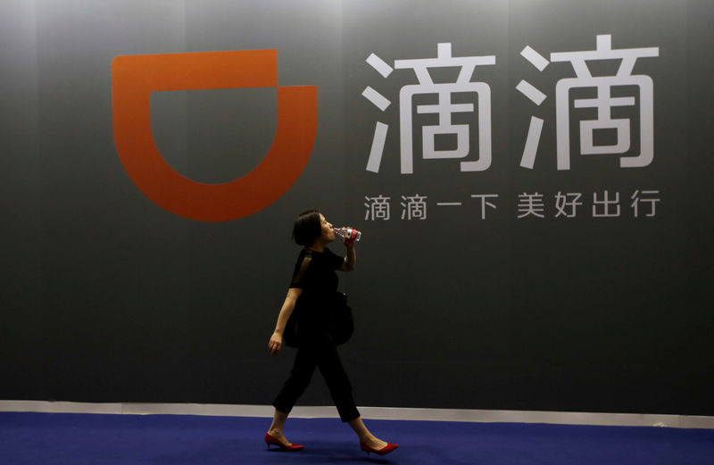 © Reuters. FILE PHOTO: A woman walks past Didi Chuxing's booth at the GMIC in Beijing