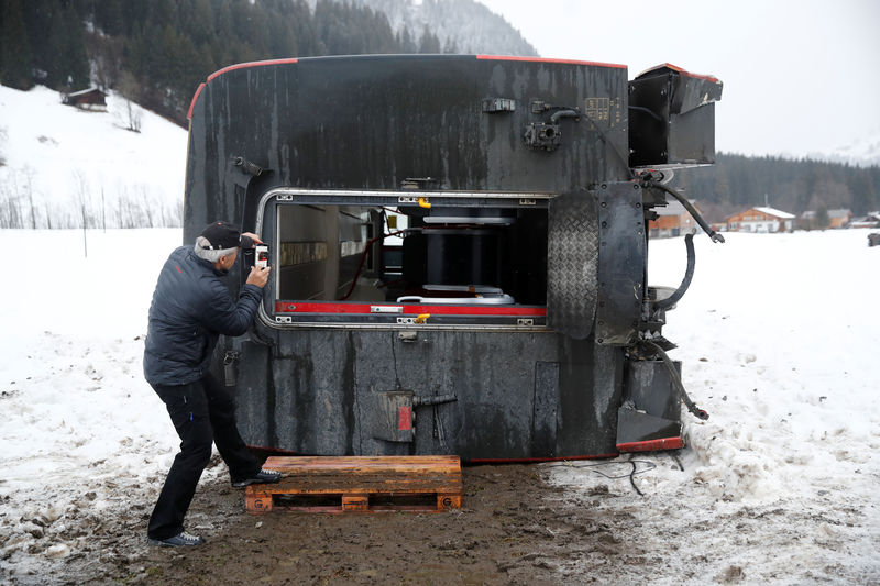 © Reuters. A man takes pictures of a carriage of the MOB train lying on its side after if was pushed out of the tracks by gusts of wind during storm Eleanor near Lenk