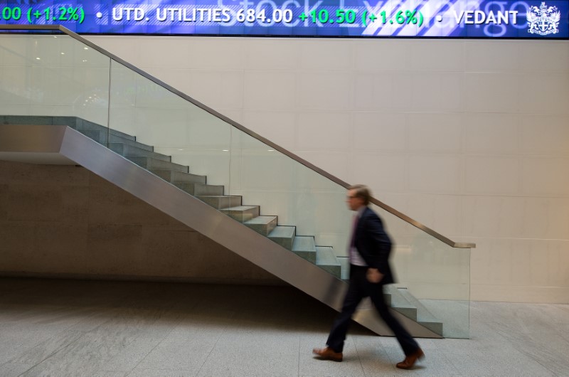 © Reuters. A man walks under an electronic information board at the London Stock Exchange in the City of London