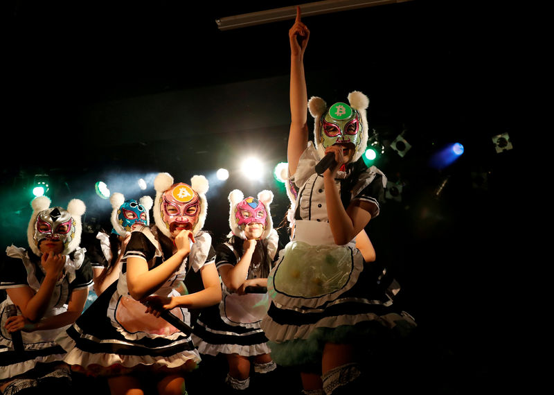 © Reuters. Members of Japan's idol group "Virtual Currency Girls" wearing cryptocurrency-themed masks perform in their debut stage event in Tokyo
