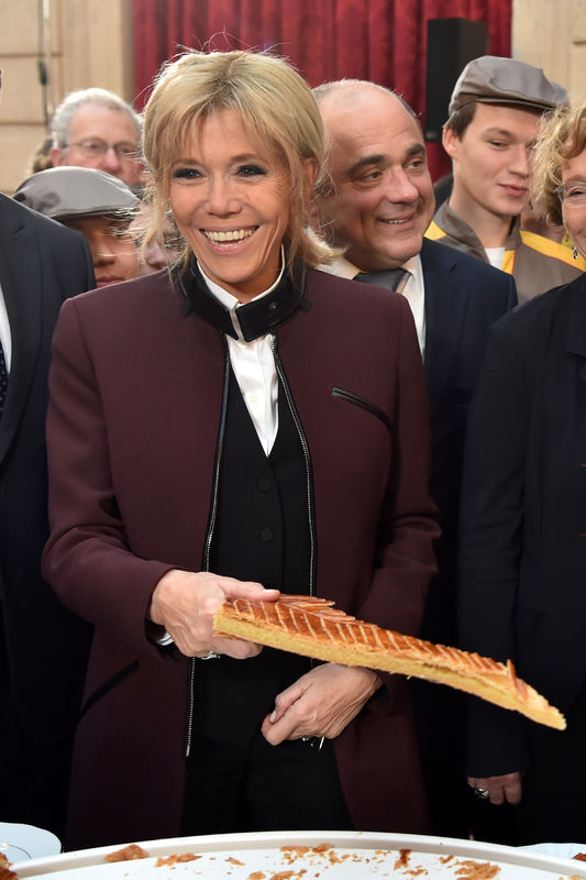 © Reuters. Brigitte Macron, wife of French President Emmanuel Macron, holds a slice of a traditional epiphany cake during a ceremony at the Elysee Palace in Paris