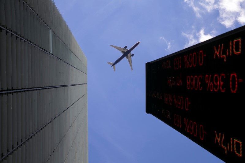 © Reuters. A plane flys above an electronic board displaying market data outiside the Tel Aviv Stock Exchange, in Tel Aviv, Israel