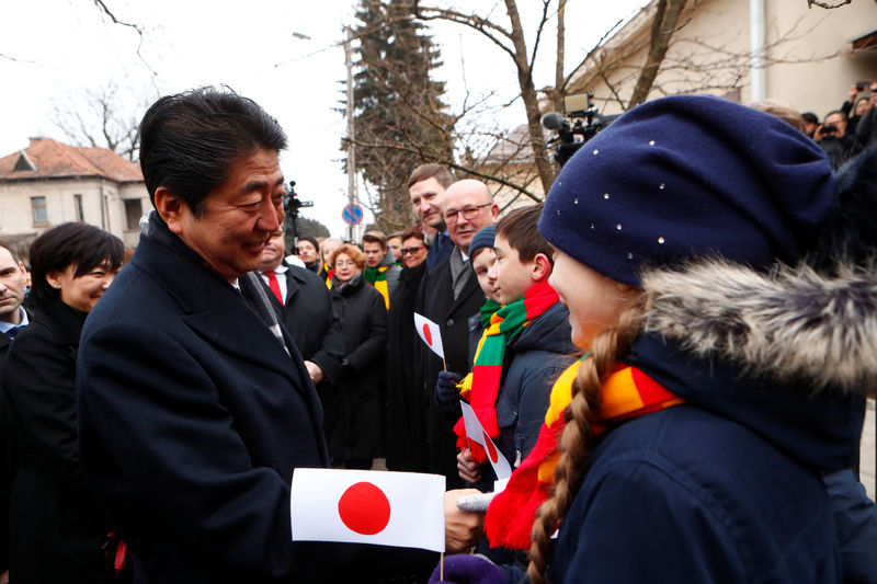 © Reuters. Japan's Prime Minister Shinzo Abe greets children holding Japanese flags, as he arrives to visit a former home of Chiune Sugihara, a Jew-saving Japanese diplomat in Kaunas