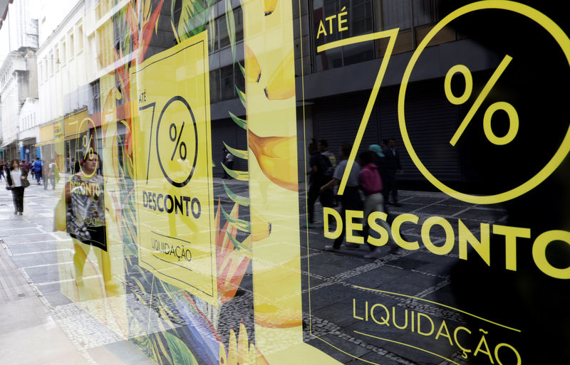 © Reuters. People walk past a store with signboards offering 70% off on store products in downtown Sao Paulo