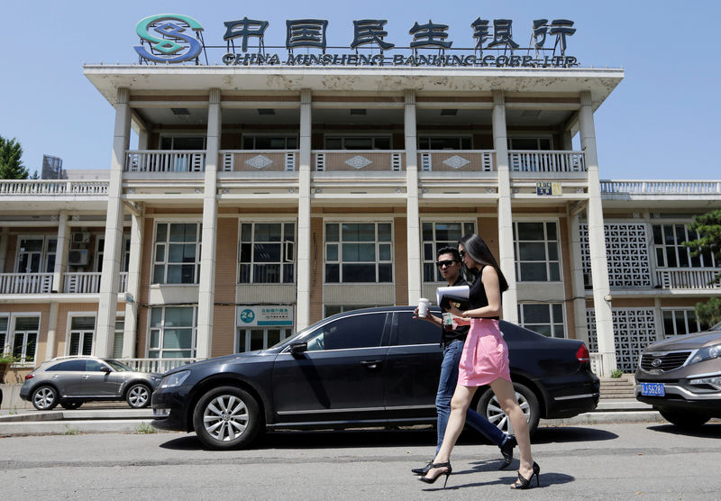 © Reuters. FILE PHOTO: People walk past a branch of China Minsheng Bank in Beijing