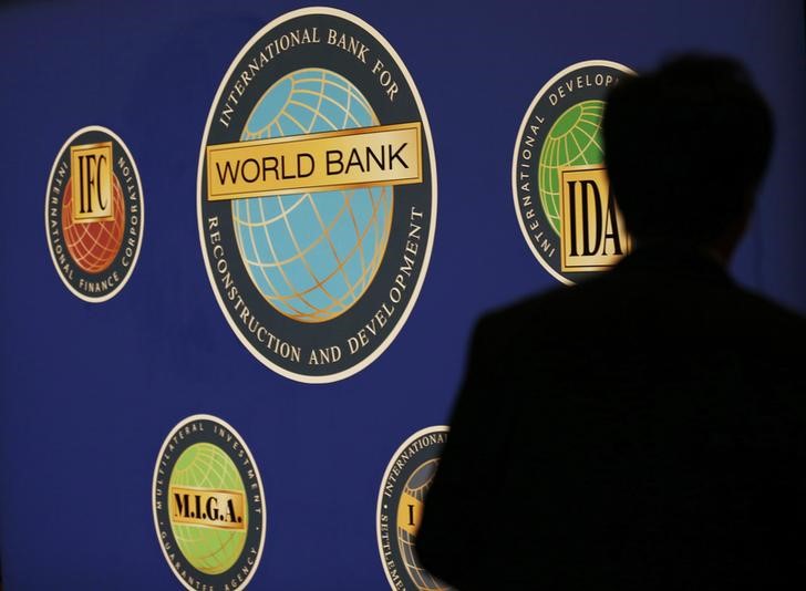 © Reuters. A man is silhouetted against the logo of the World Bank at the main venue for the IMF and World Bank annual meeting in Tokyo