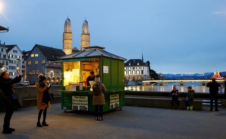 © Reuters. The Grossmuenster church is seen behind a stall offering roasted chestnuts in Zurich
