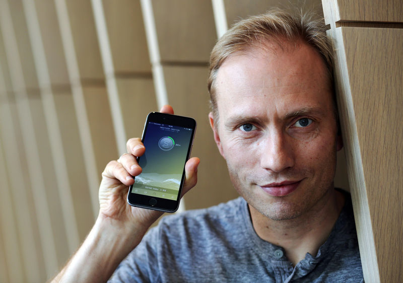 © Reuters. FILE PHOTO: Co-founder of Sweatcoin Oleg Fomenko poses with the app open on a phone at his London office
