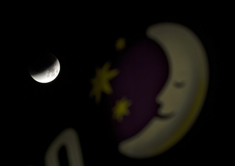 © Reuters. The shadow of the Earth is seen on the moon at the start of a total lunar eclipse, next to a Premier Inn hotel sign in Dover