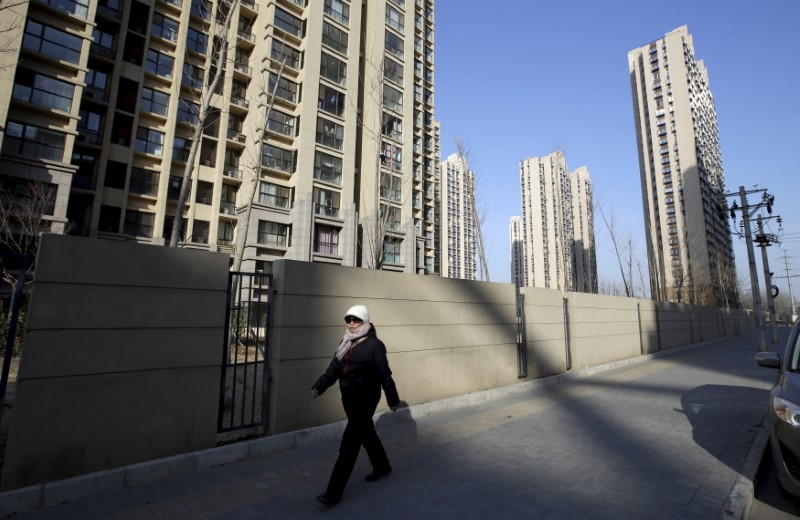 © Reuters. A woman walks past a residential compound in Beijing's Tongzhou district