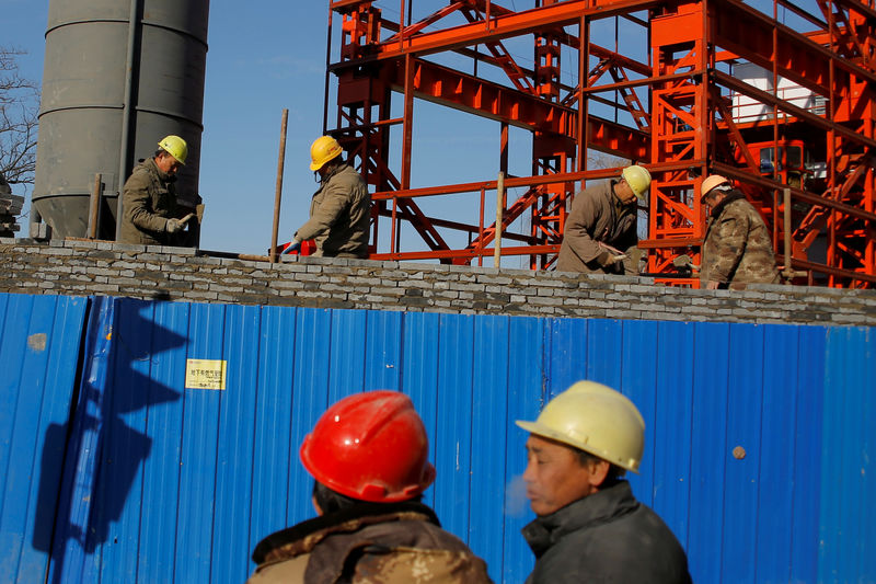 © Reuters. FILE PHOTO: Workers lay bricks to build a wall around a construction site in Beijing