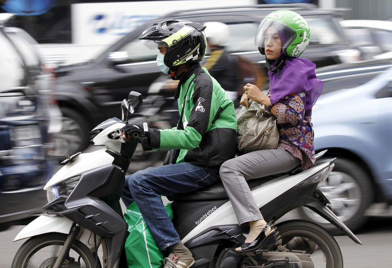 © Reuters. FILE PHOTO: Woman rides on the back of a motorbike, part of the Go-Jek ride-hailing service, on a busy street in central Jakarta