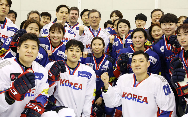 © Reuters. South Korean President Moon Jae-in poses for photographs with South Korean women's and men's ice hockey team players during his visit to Jincheon National Training Center in Jincheon