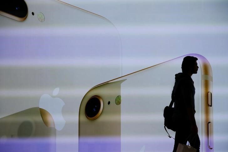 © Reuters. A customer walks past a large screen at the new Apple Visitor Center in Cupertino