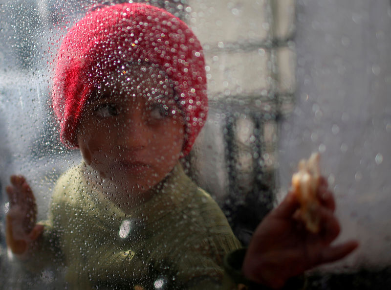 © Reuters. Palestinian girl looks through a plastic sheet as raindrops are seen, outside her family's house in Al-Shati refugee camp in Gaza City