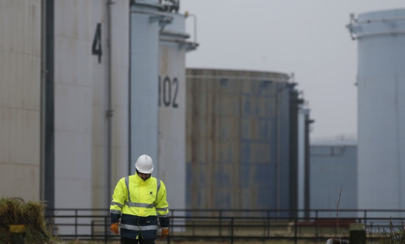 © Reuters. A worker walks past oil tanks at the Total refinery in Grandpuits