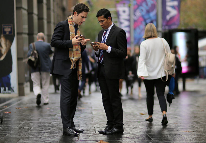 © Reuters. FILE PHOTO: Businessmen use their phones as they stand in the central business district (CBD) of Sydney in Australia