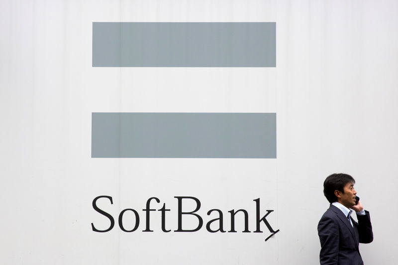 © Reuters. FILE PHOTO: A man talks on the phone as he stand in front of an advertising poster of the SoftBank telecommunications company in Tokyo