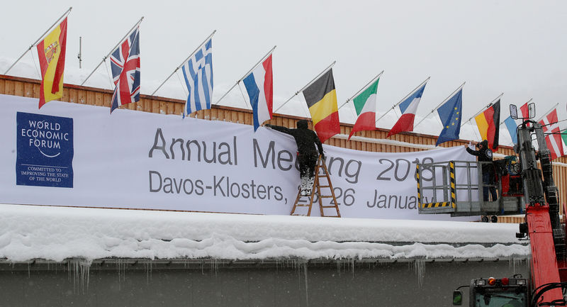 © Reuters. Workers fix a banner on the frontage of the congress centre in the Swiss mountain resort of Davos