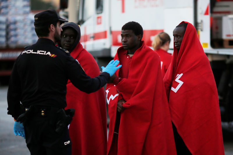 © Reuters. Imigrantes são conduzidos por policial espanhol em Málaga, na Espanha