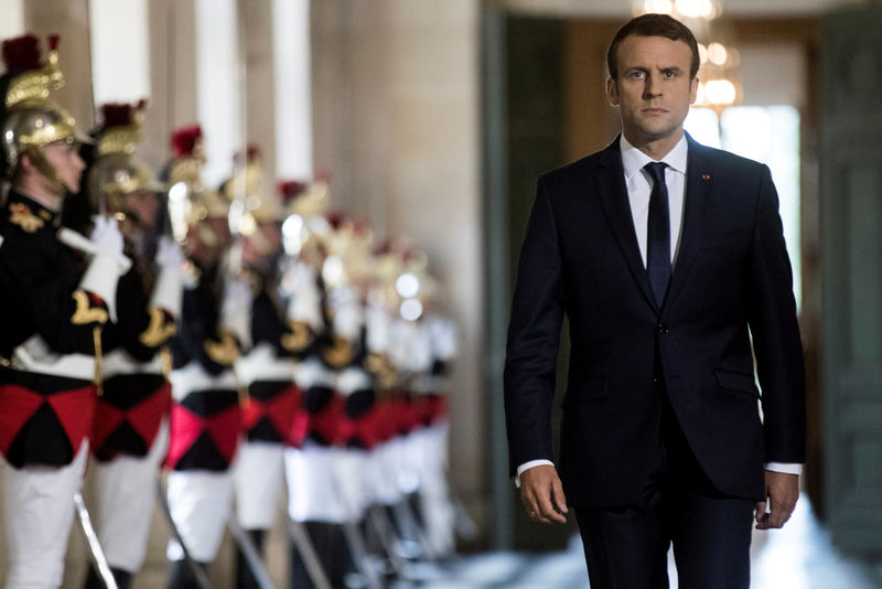 © Reuters. FILE PHOTO: French President Emmanuel Macron  walks through the Galerie des Bustes (Busts Gallery) to access the Versailles Palace in July 2017.