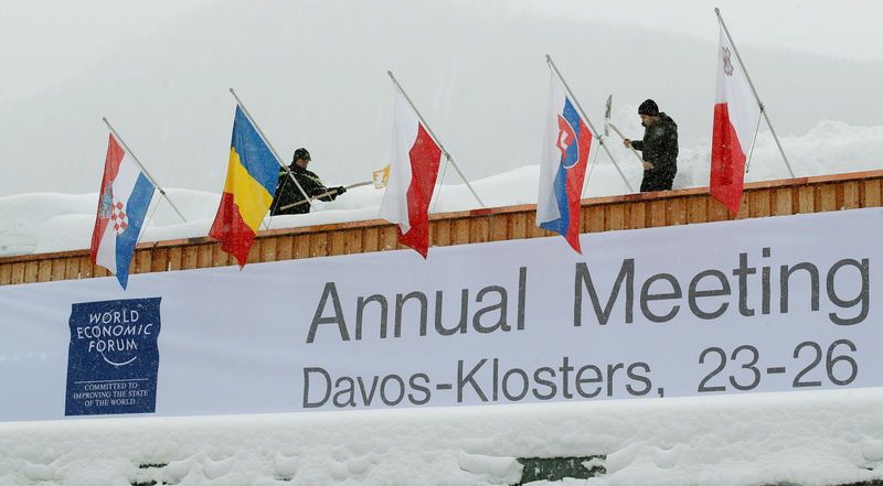 © Reuters. Workers shovel snow from the roof of the congress centre in the Swiss mountain resort of Davos
