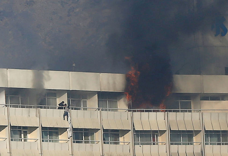 © Reuters. Un hombre intenta escapar del hotel Intercontinental de Kabul durante un ataque de hombres armados