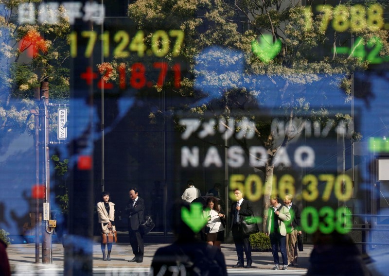© Reuters. People are reflected in a display showing the Nikkei average and the NASDAQ average of the U.S outside a brokerage in Tokyo